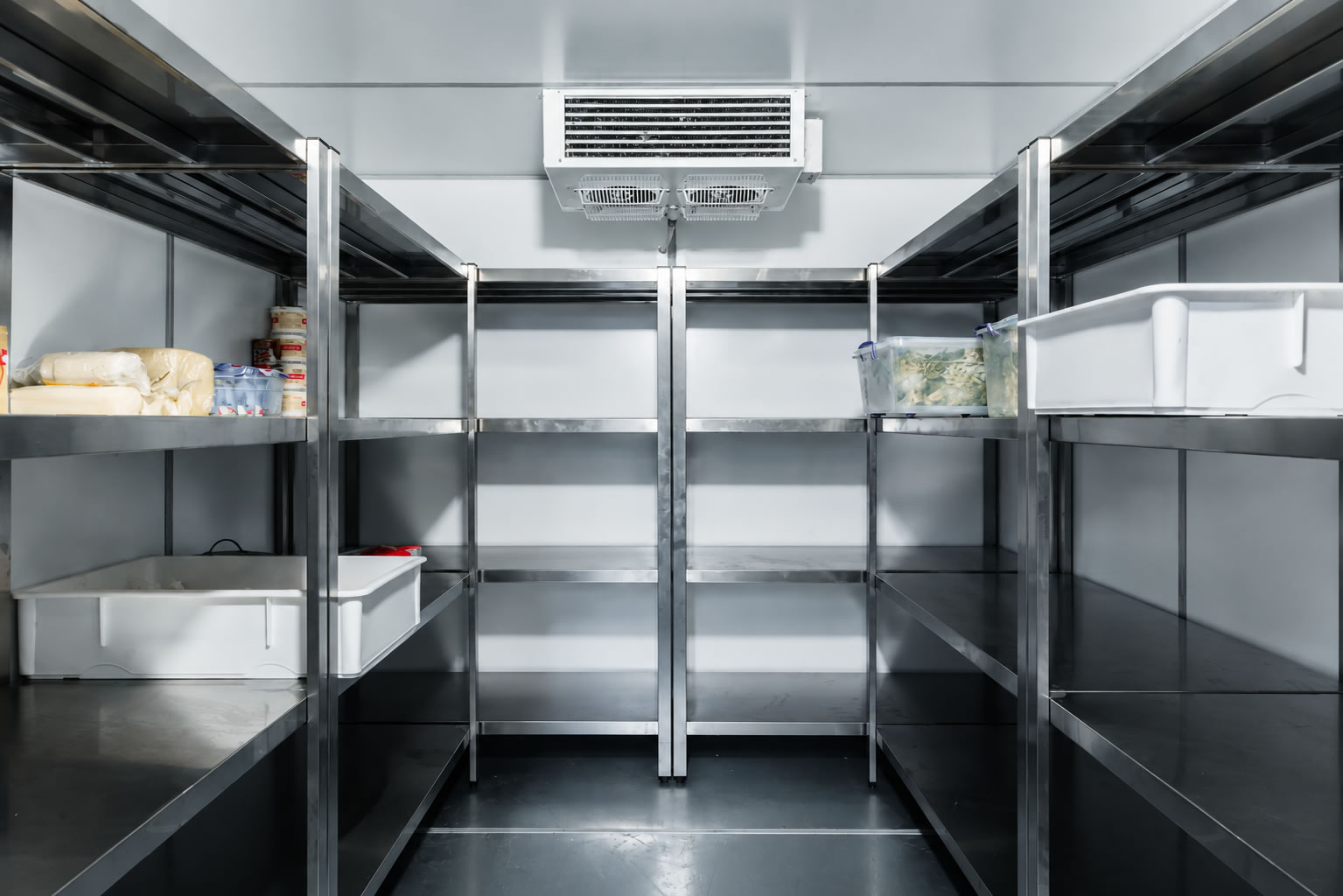 Técnico ingresando a cuarto frío industrial con racks y montacargas
